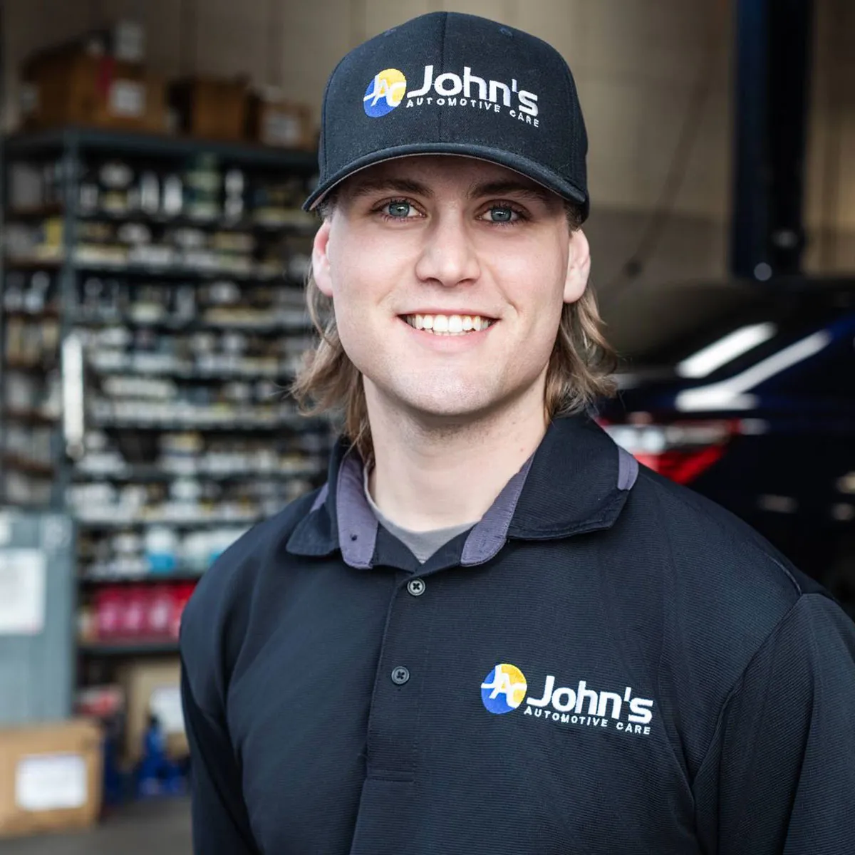 Smiling mechanic in John's Automotive Care attire.