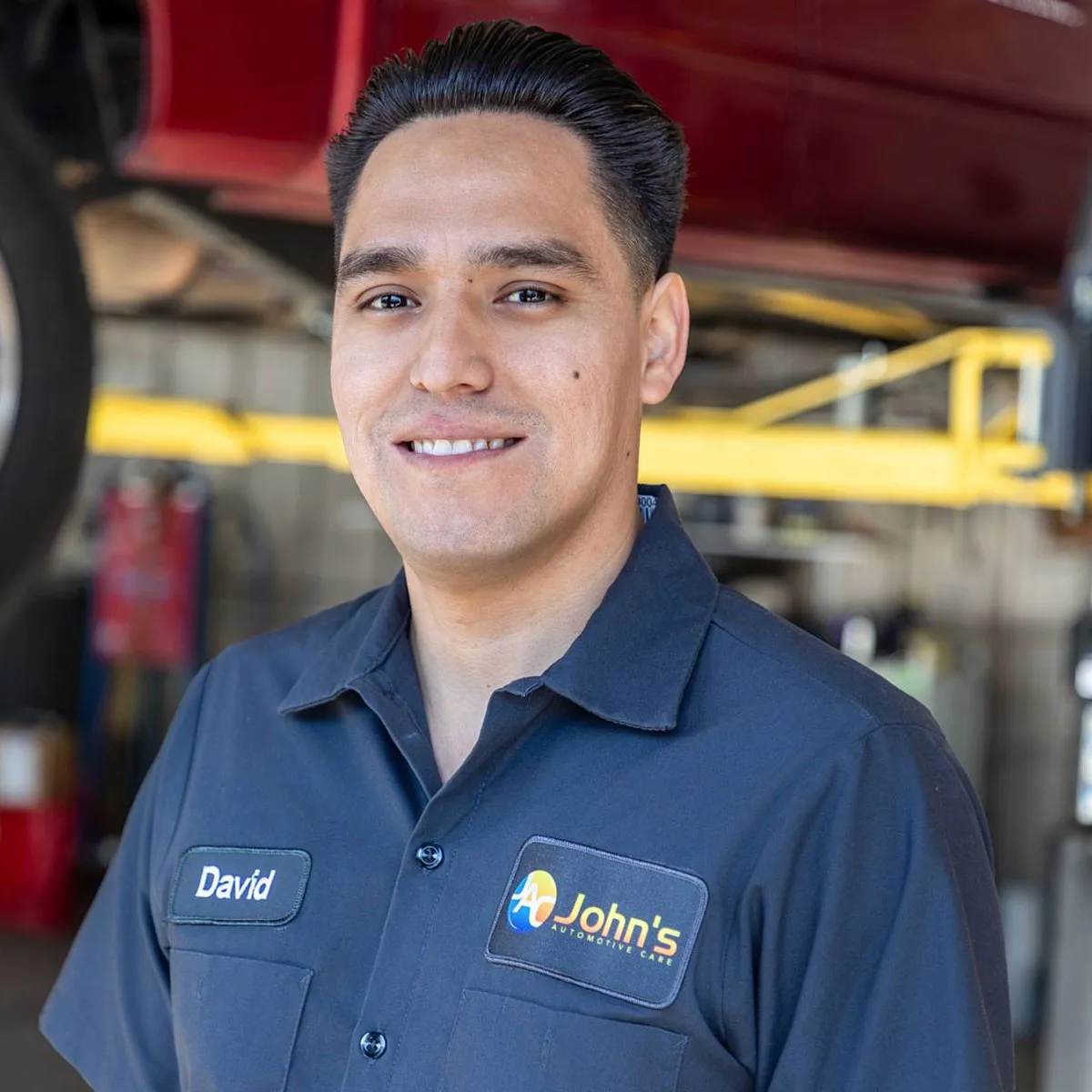 Smiling mechanic at John's Automotive Care garage.