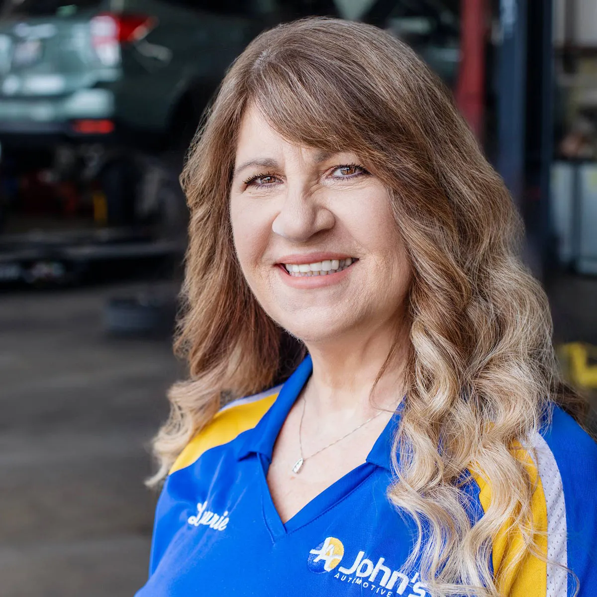 Smiling woman in a blue automotive uniform.